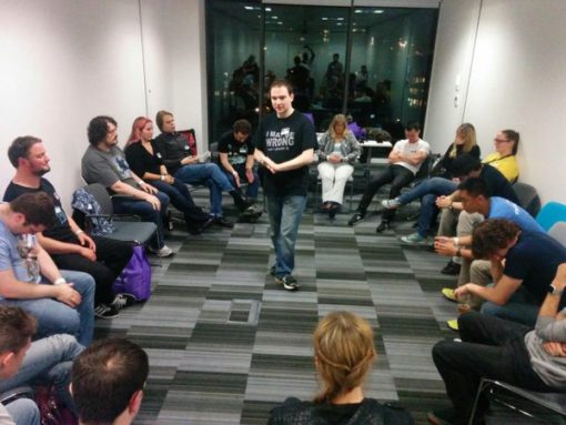 A group of people in a circle playing Werewolf with a moderator in the centre